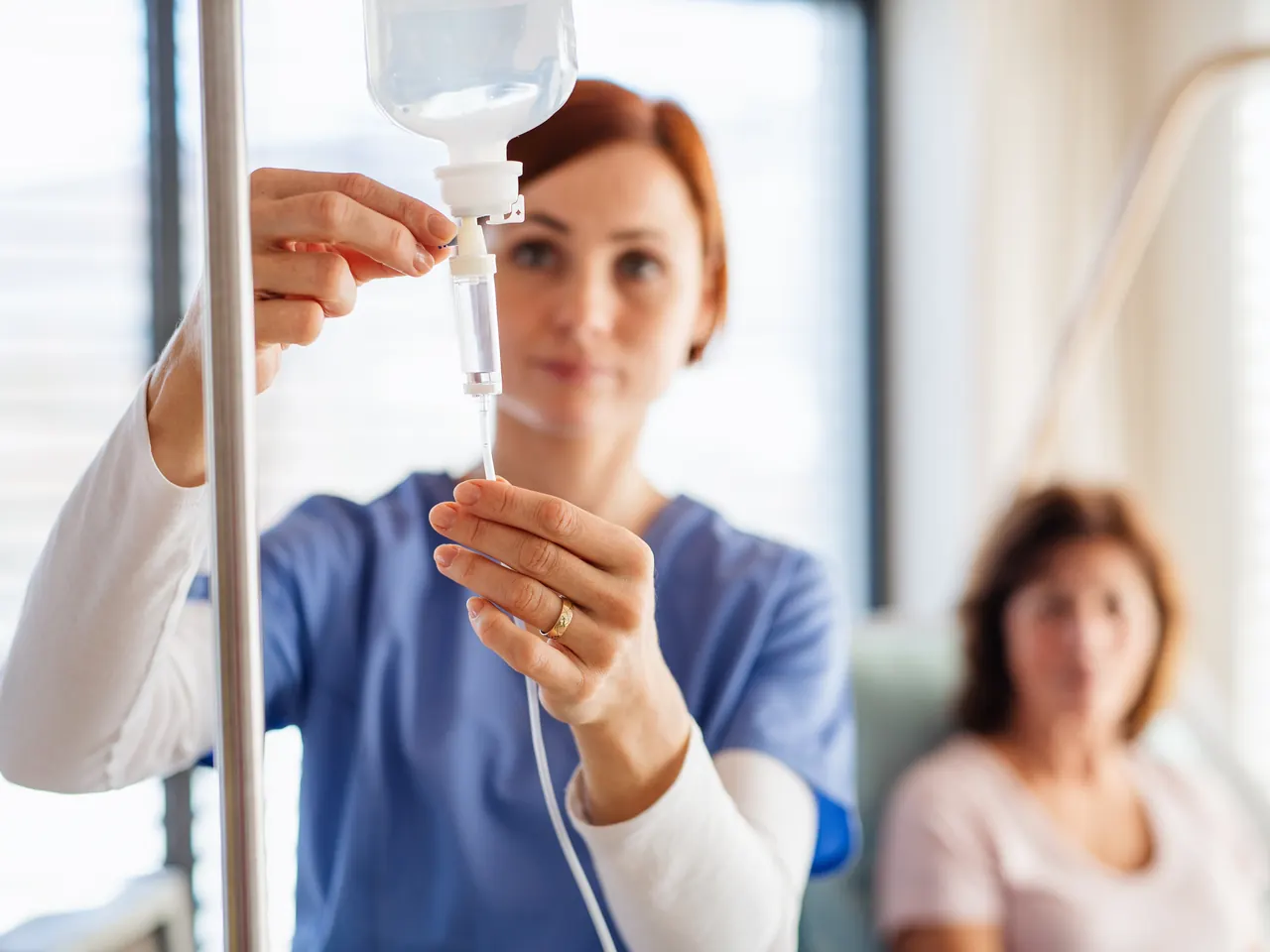 A registered nurse preparing an IV drip for a seated client